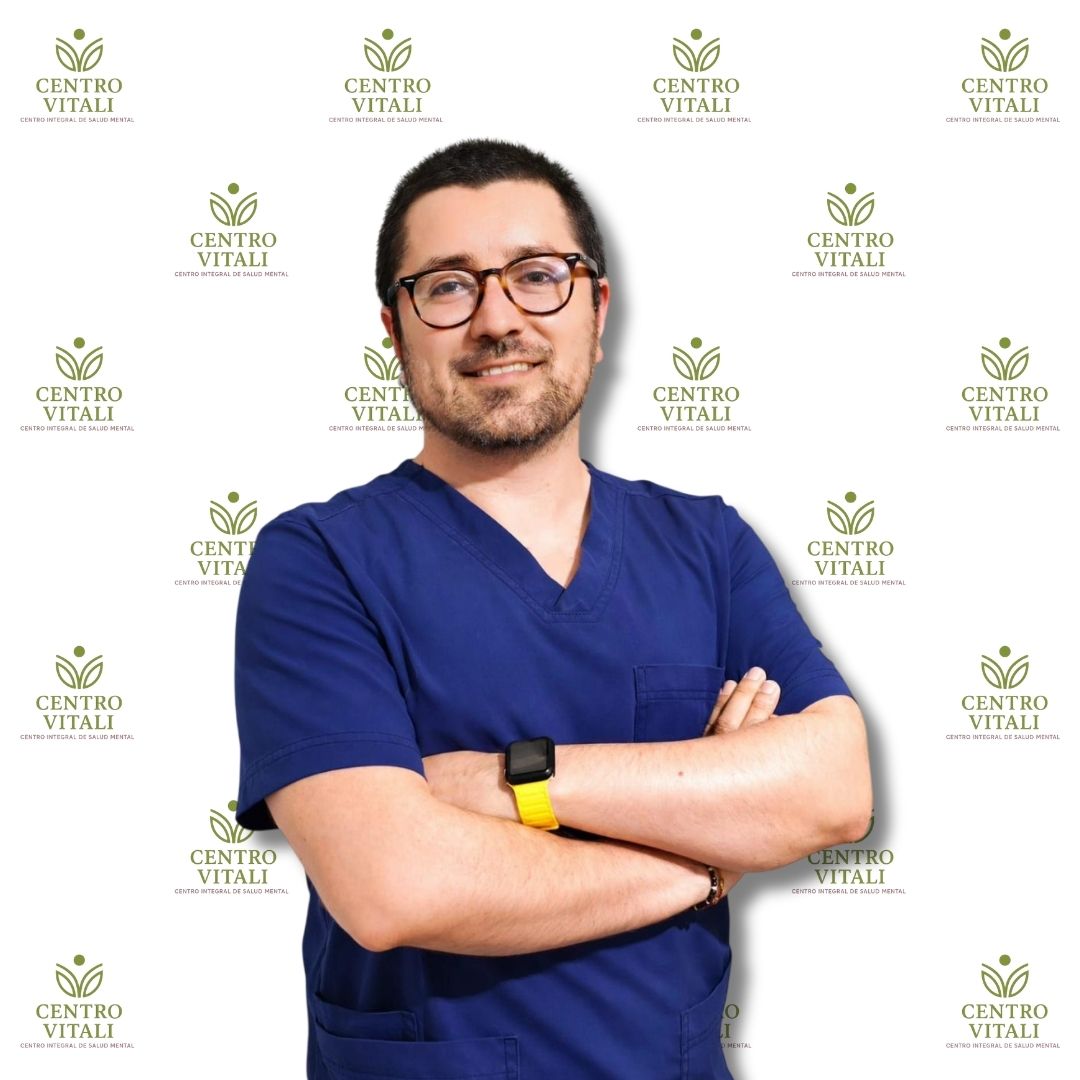 Profesional de la salud con uniforme azul, sonriendo frente a fondo con logo de Centro Vitali.